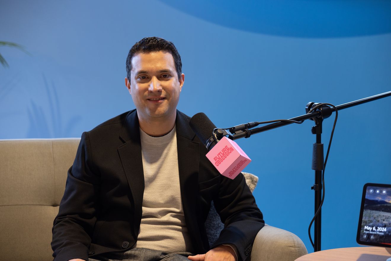 A smiling guest on a sofa beside a microphone on a boom arm