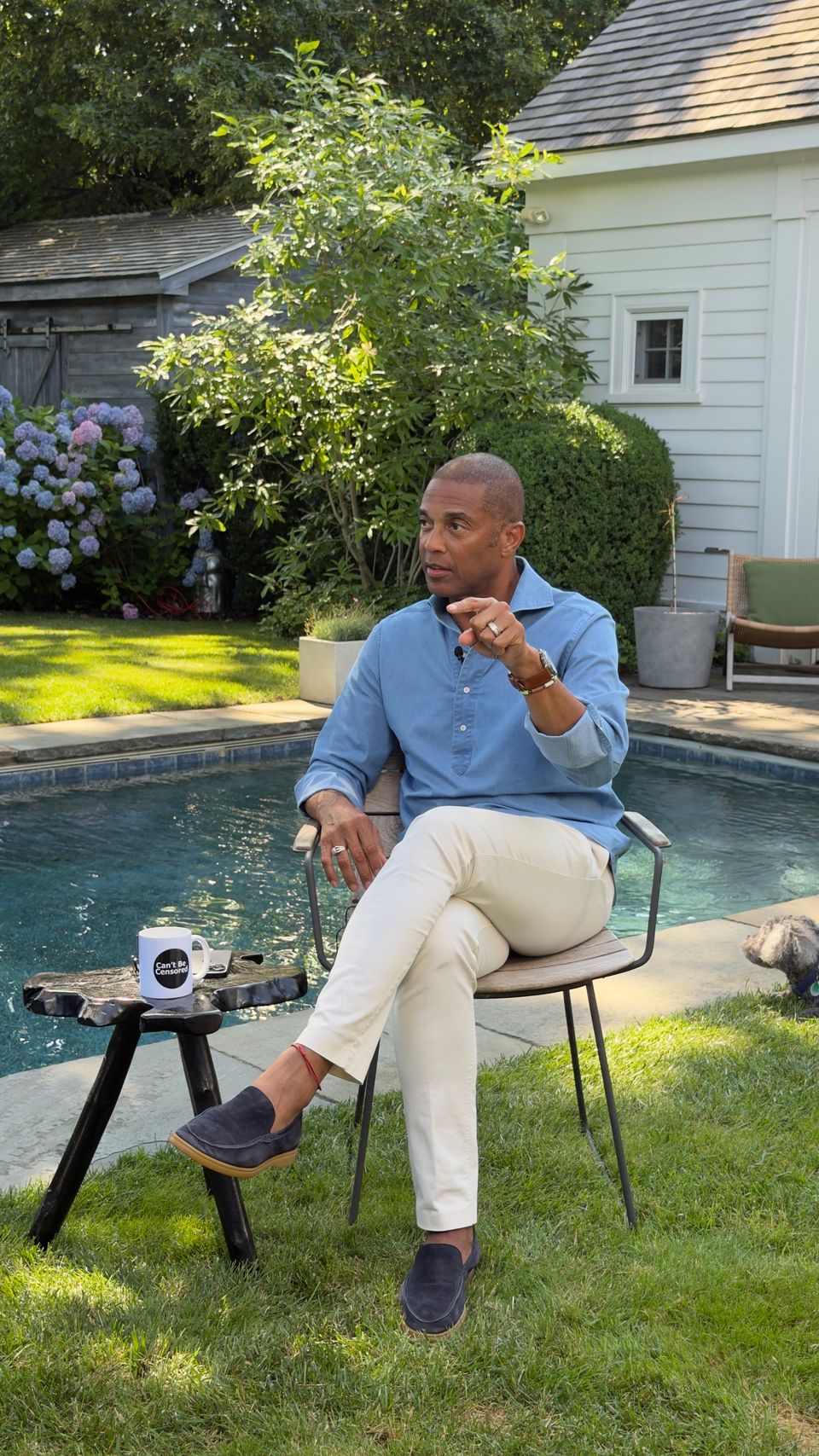 A guest seated in a garden beside a swimming pool, being filmed on location