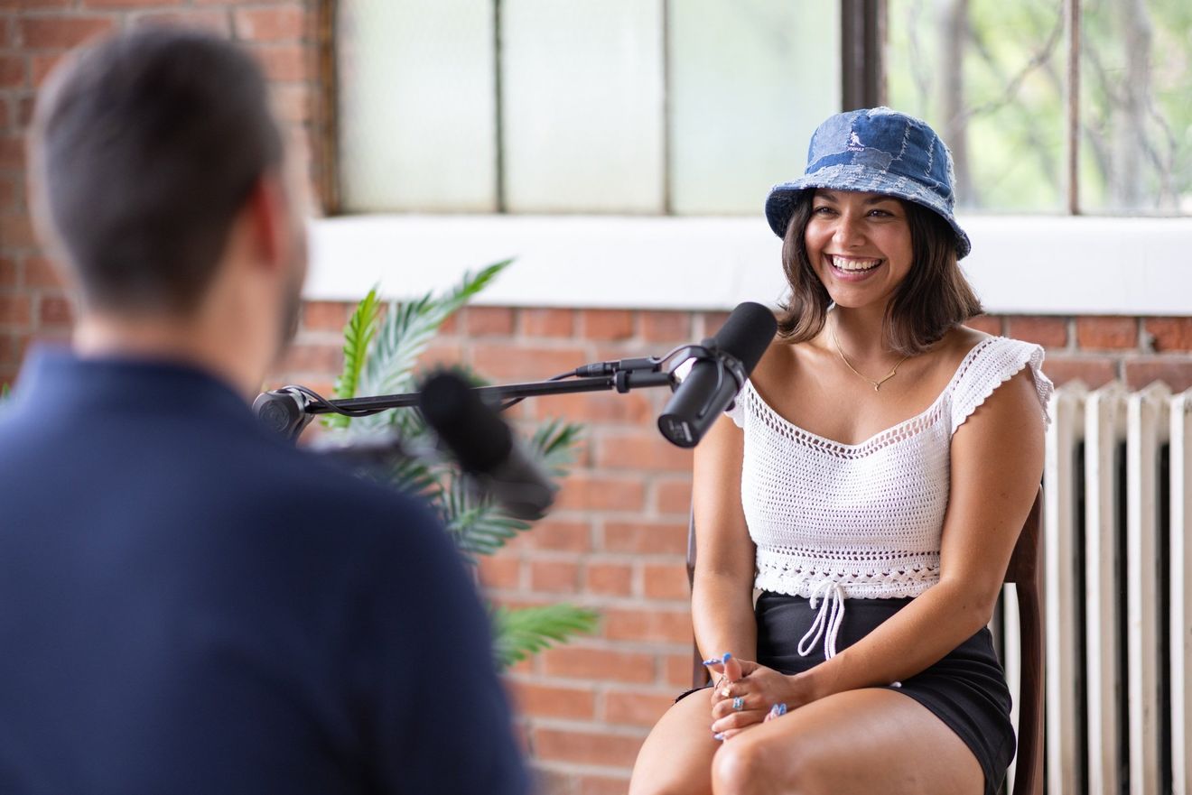 Guest in a blue bucket hat laughing at a microphone in the brick loft