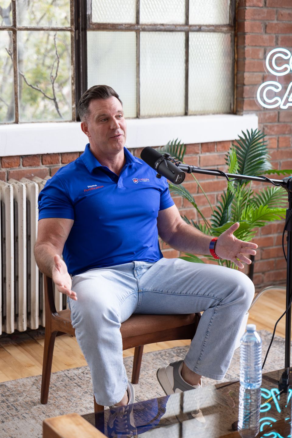 Guest seated at a microphone in front of a brick wall and big windows