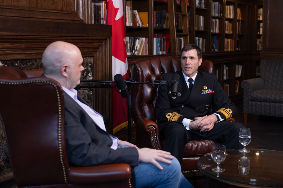 Two men talking in leather chairs in a library